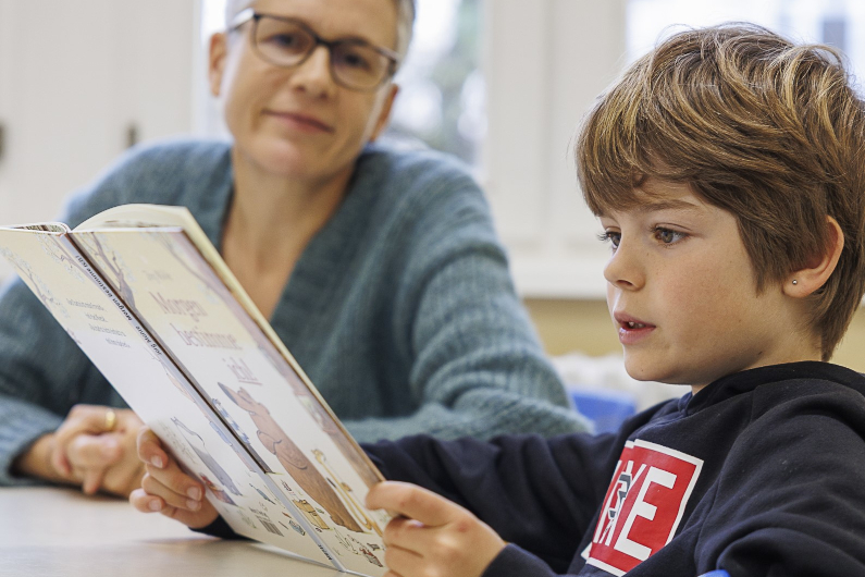 Eine Frau hilft einem Kind beim Lesen eines Buches